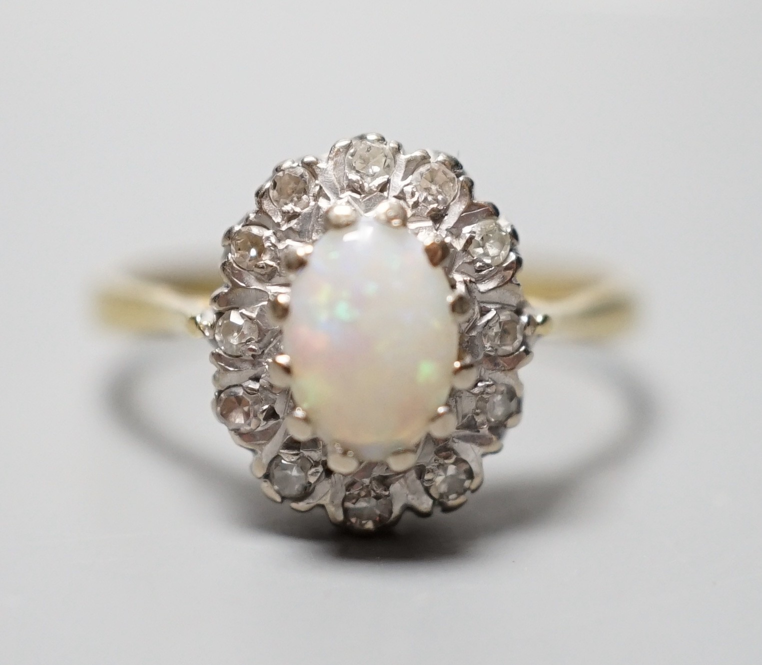 A modern 18ct gold, white opal and diamond chip set oval cluster ring, size N, gross weight 3.6 grams.